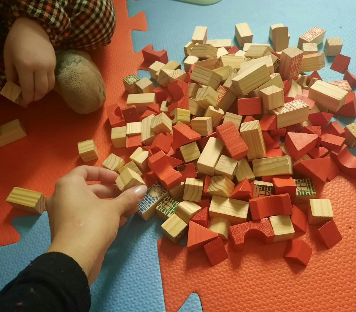 A child and an adult exploring colorful wooden building blocks together